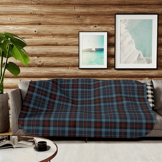 Plaid blanket draped over a sofa in a living room with framed artwork on the wall.