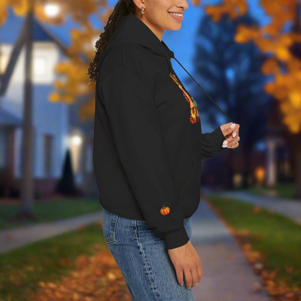 Person wearing a black hoodie with a small orange pumpkin design on a white background