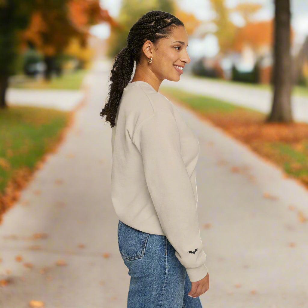 Woman wearing a beige sweatshirt with a small black design on a white background