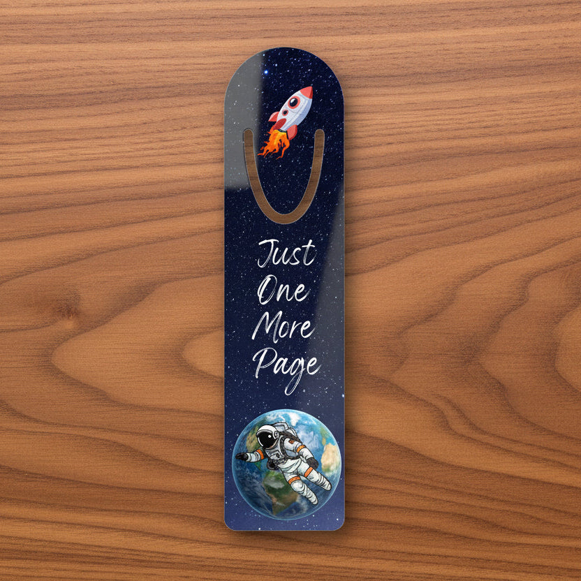 Space-themed bookmark of a rocket and astronaut illustration with the words Just One More Page
