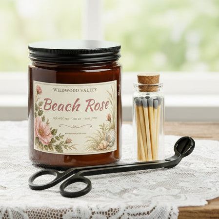 Candle jar labeled 'Beach Rose' with a wick trimmer, matches and a lighter